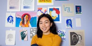 artemisia luk posing in front of a wall of her art