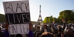 Black Lives Matter sign being held up in front of the Eiffel Tower