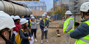 Students stand outside the science building wearing construction hats