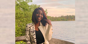 Adwoa Difie Antwi ’21 posing in front of Lake Waban with a sunset sky
