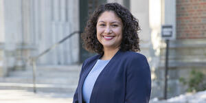 A portrait of Professor Natali Valdez, shown from waist up. She wears a dark blue blazer and is smiling at camera.