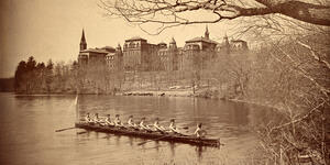 The class crew of 1894 rows on Lake Waban, with College Hall in the background.