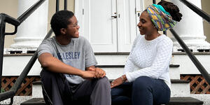 Izzy Torkornoo ’23 and Liseli Fitzpatrick speak to each other while sitting on the stairs of Harambee House.