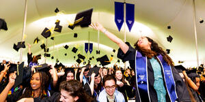Students toss their graduation caps in the air at the end of commencement.
