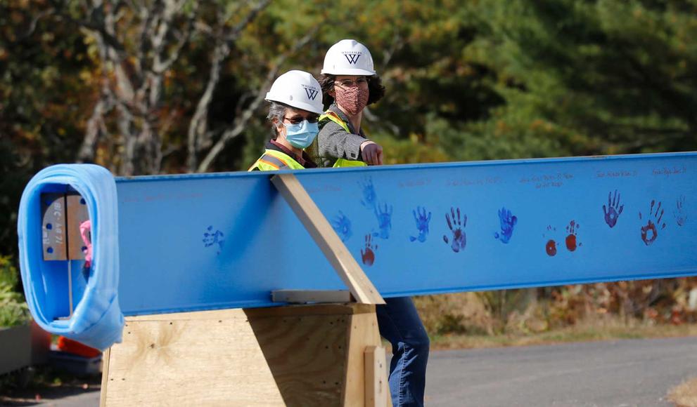 two people in construction gear looking at a construction beam