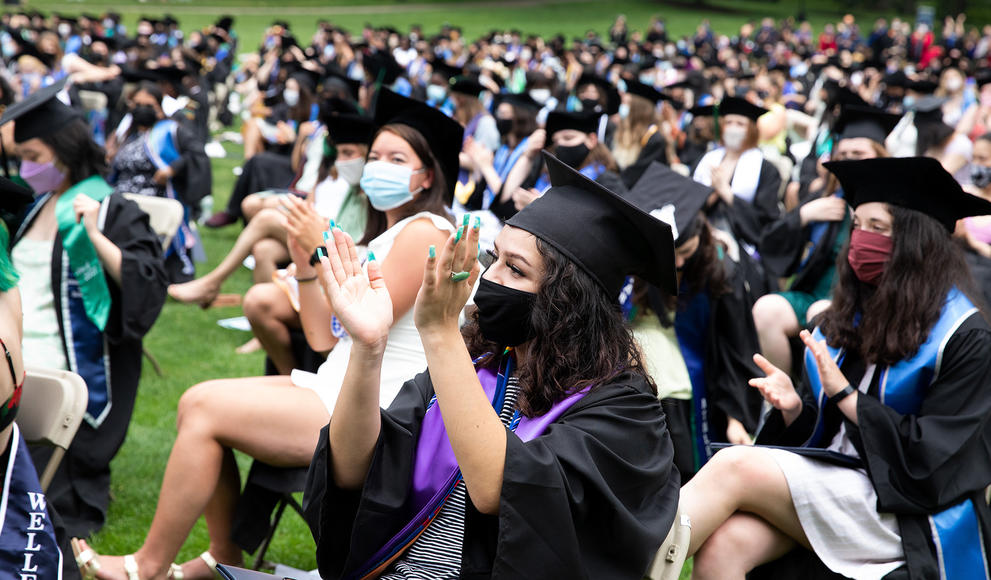 Students seated in the audience during commencement, applauding.