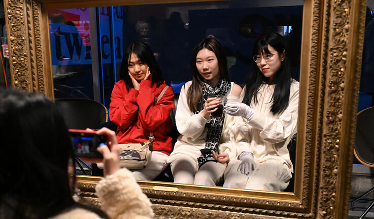 Three students pose for a photo within a gold frame.