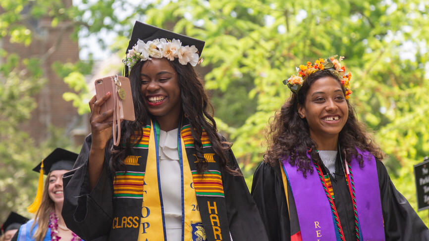 Two members of the class of 2019 walk into the tent for the commencement exercises. 