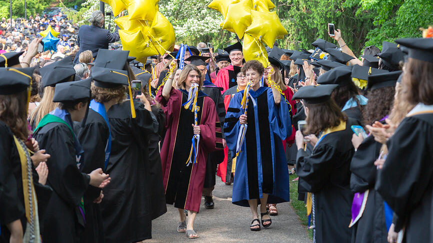 Class deans process in carrying yellow star balloons