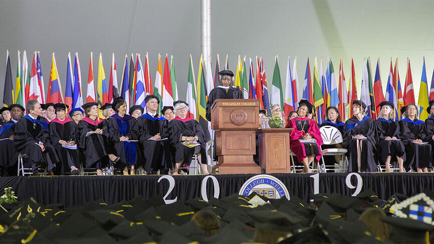 Anita Hill speaks to a crowd of people. The stage reads 2019.