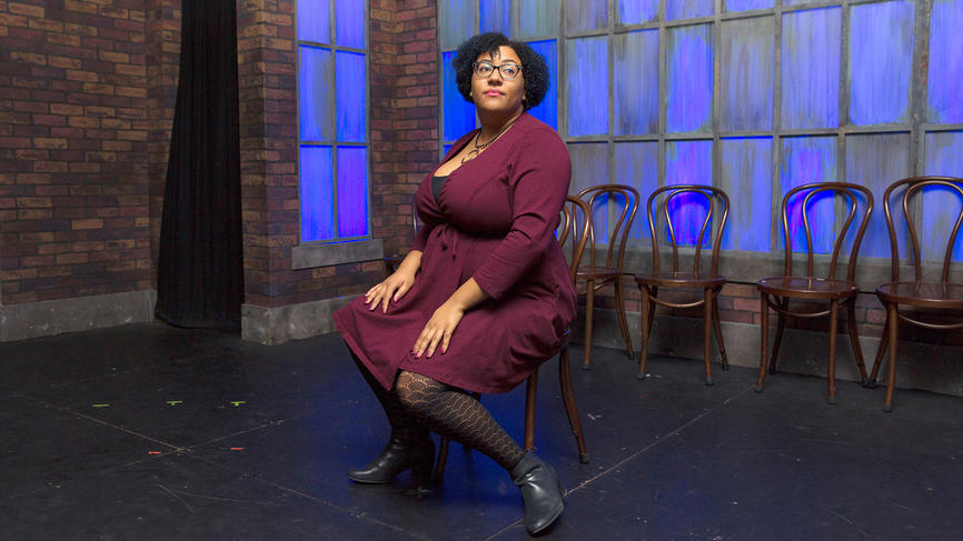 A woman sits on a chair on stage