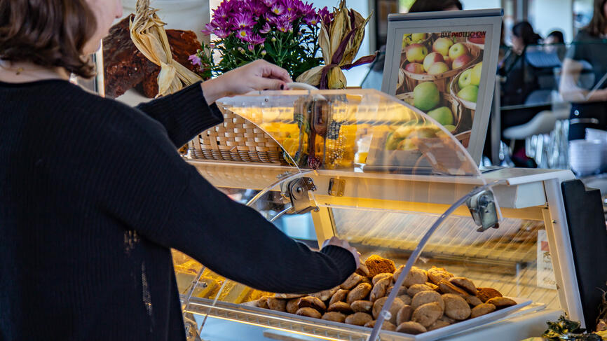 A student picks out a cookie from a large container. 