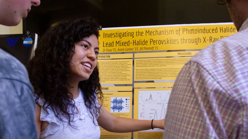 A student shows her poster to a group of people standing by