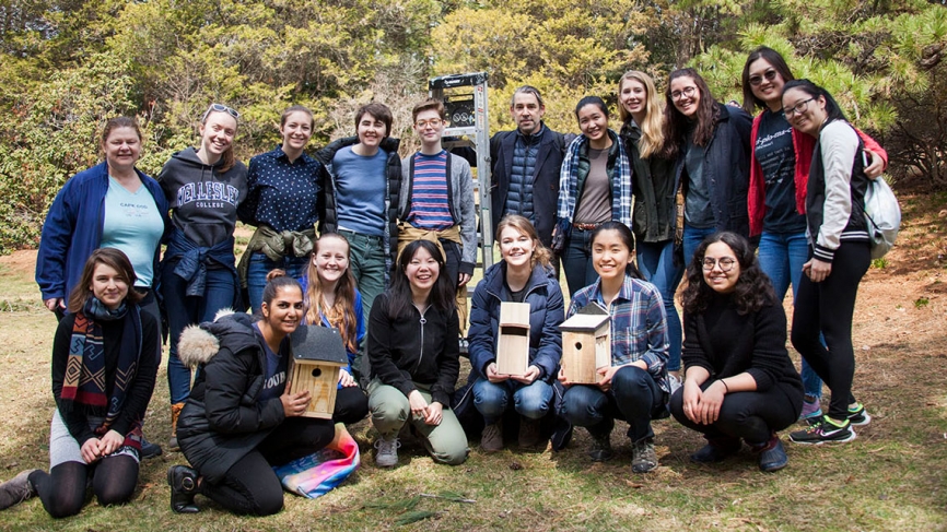 Andrew Mowbray and his students stand in a group photo outside wth their bird boxes.