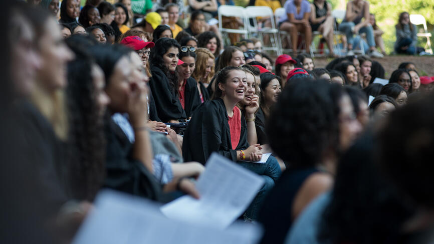 A student laughs amid a crowd of students in the theater. 