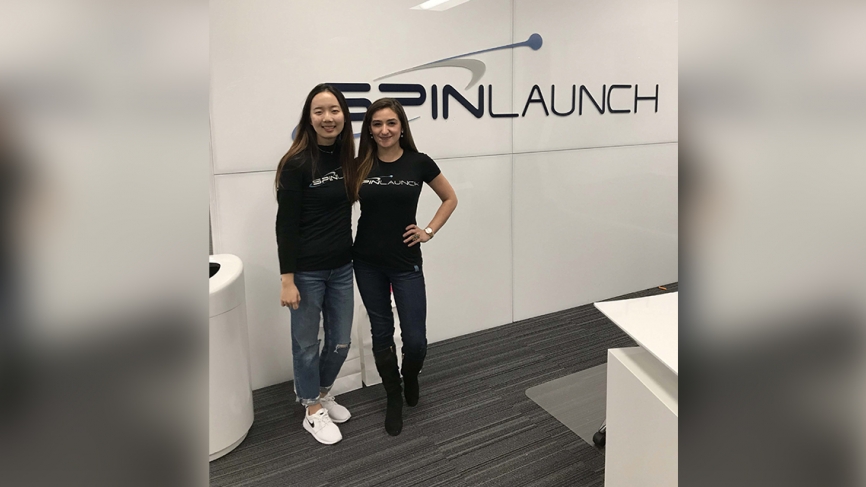 Two women stand in front of branding that says "SpinLaunch."