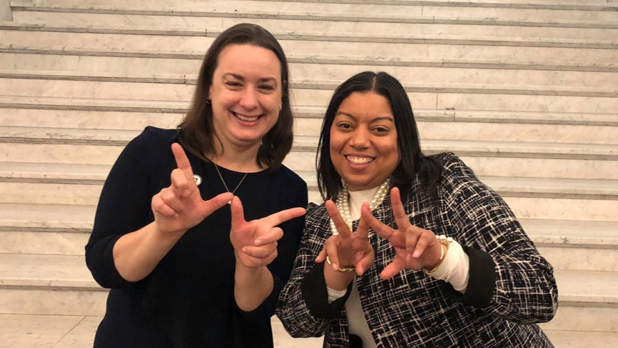 Two alumnae make "W" with their hands