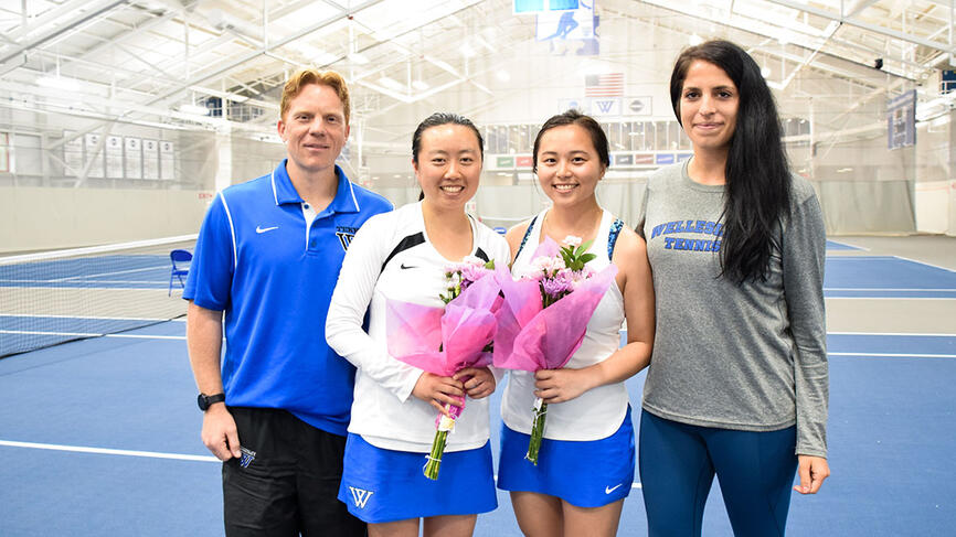 Two members of the tennis team pose with coaches on senior day