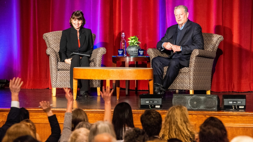 Al Gore and Sue Wagner sit on stage in front of a packed audience.
