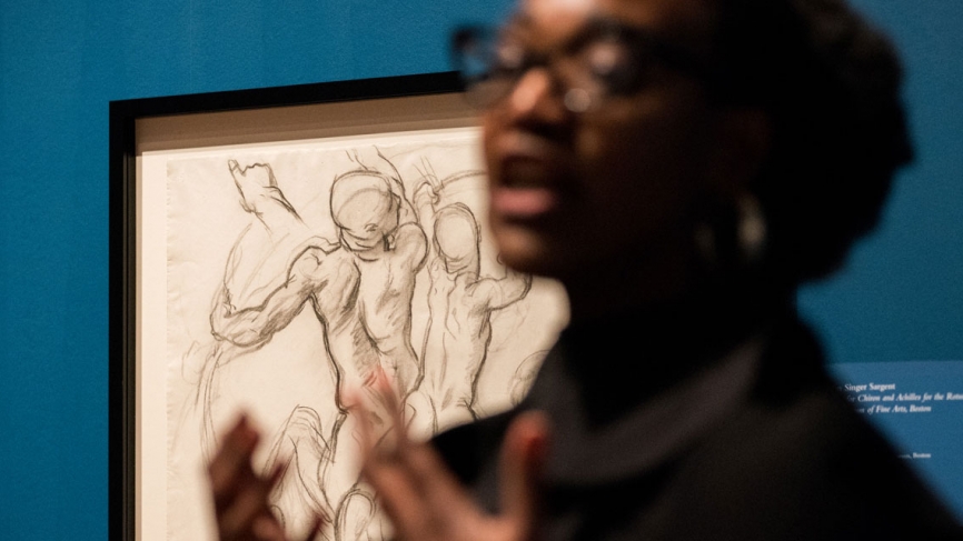 Sargent drawing in focus with Nikki speaking in foreground