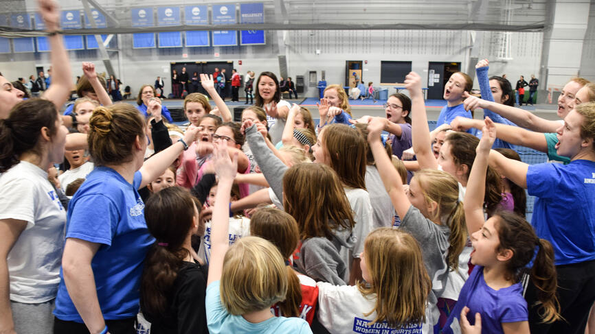 students and young girls stand in a huddle. 