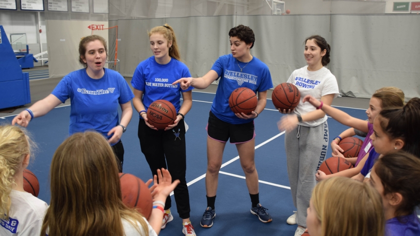A group of student athletes lead a clinic with young girls.