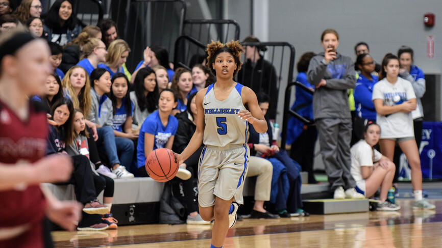 a student takes a basketball up the court, looking to make a play