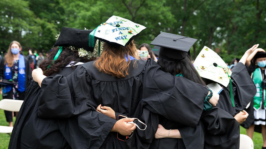 Graduating students pose for a photo with their robes and mortar boards on. Photo taken from the back.