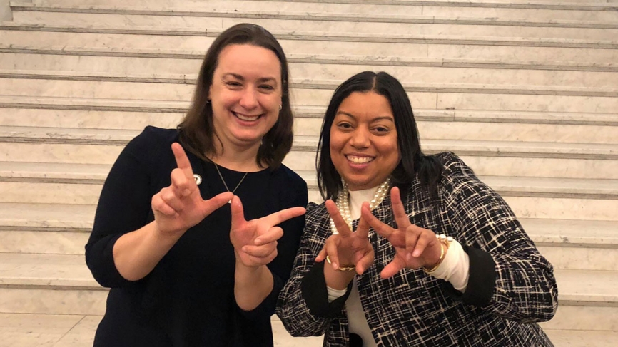 Lindsay Sabadosa and Liz Miranda form two Wellesley "W" with their hands.