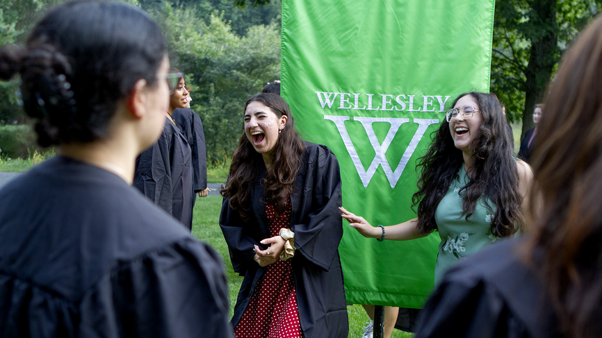 Two friends share a laugh in front of the 2025 banner.