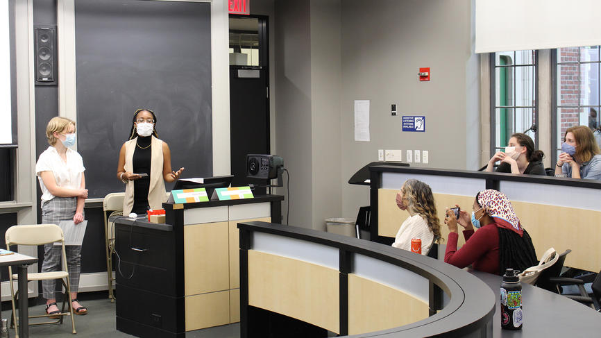 Two students make a presentation at the front of a classroom.