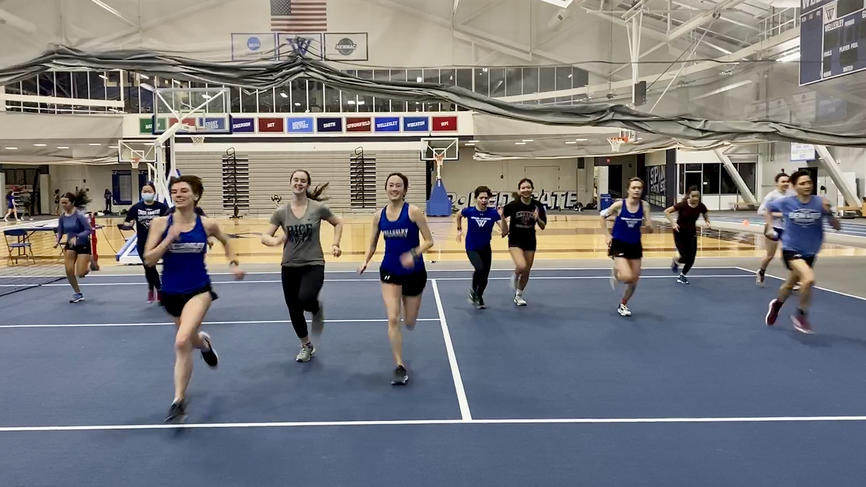 Photo of track runners running inside and toward the photographer.