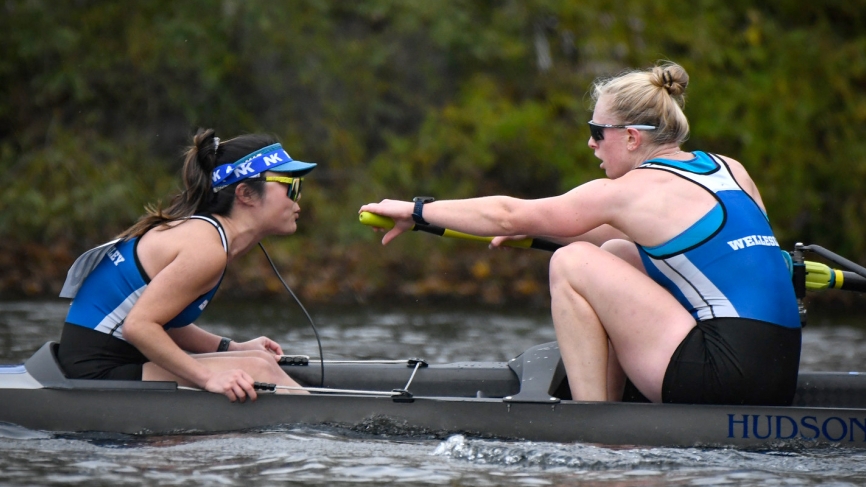 A coxswain and rower sit facing each other in a boat during a race.