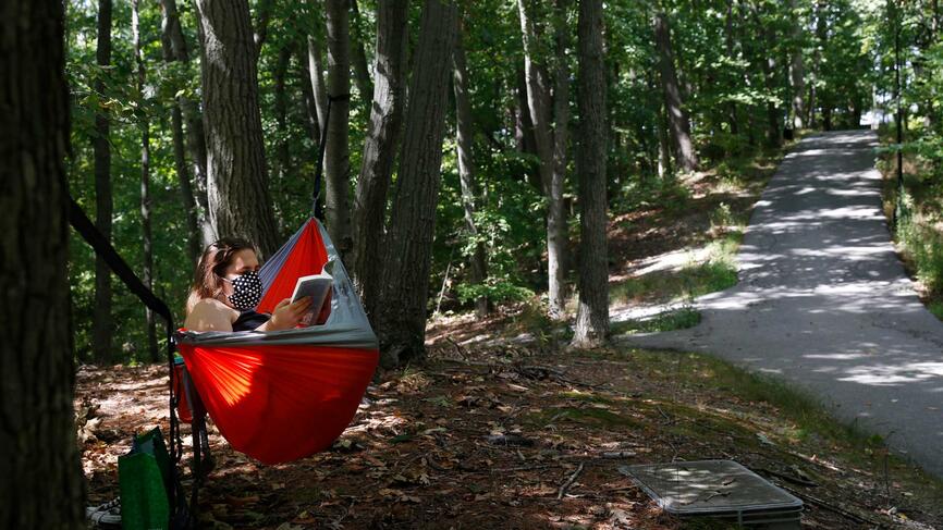 A student reading a book while sitting in a hammock