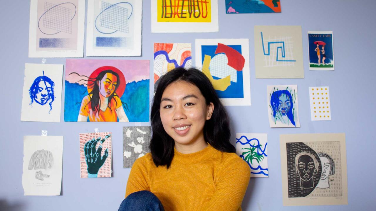 artemisia luk posing in front of a wall of her art