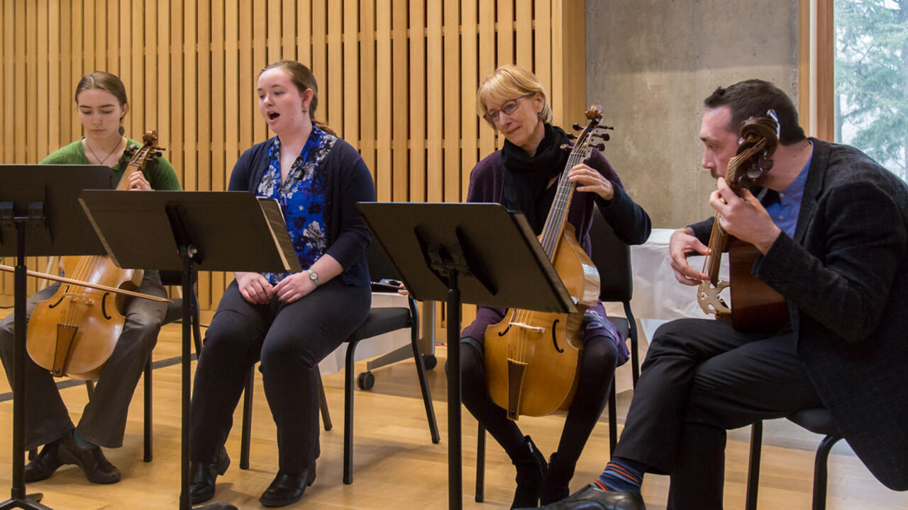 Two students and two professors play musical instruments on a stage.