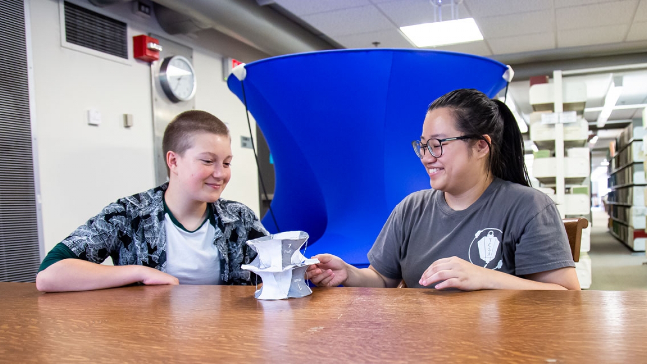 two students, Jenna Ocheltree ’22 and Silvia Yu ’21, sitting at a table in front of their math model