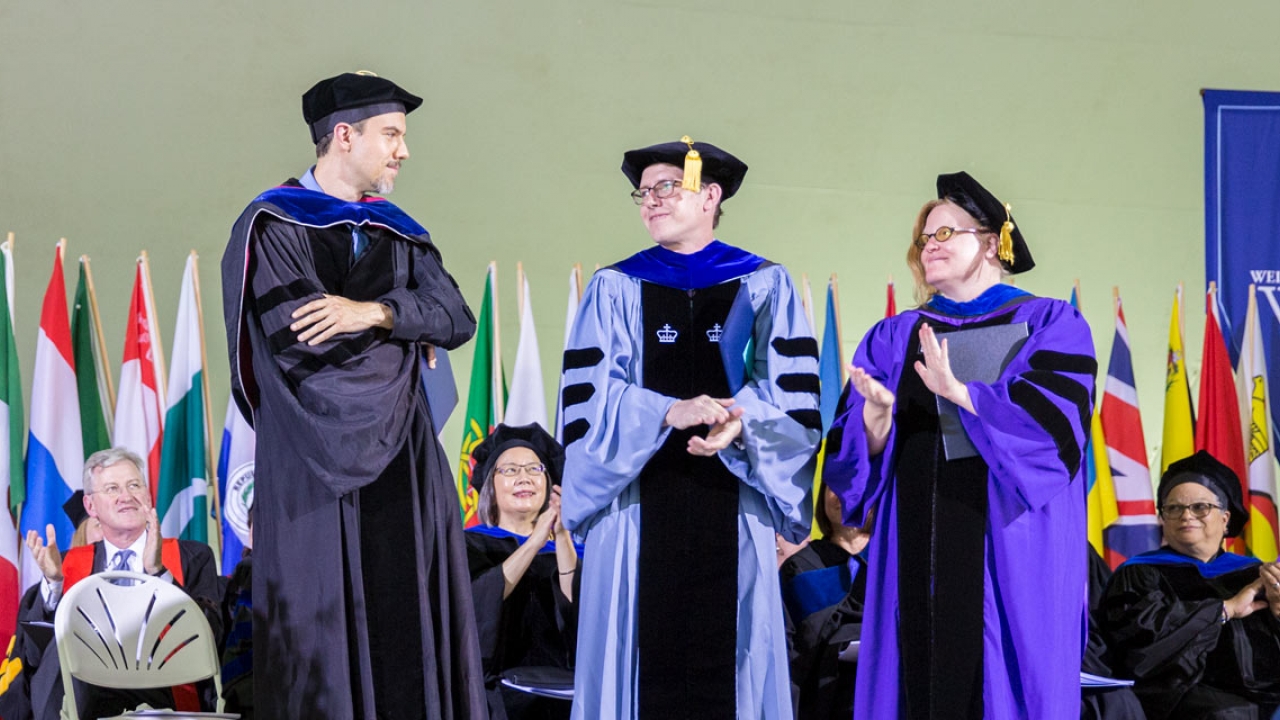 Three professors stand on stage at Wellesleys commencement exercises.