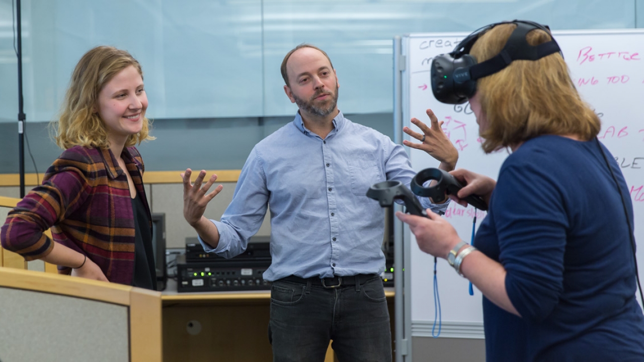 Knapp intern Kamile Lukosiute and Prof. Adam Van Arsdale watch as a user demos their human evolution virtual reality experience