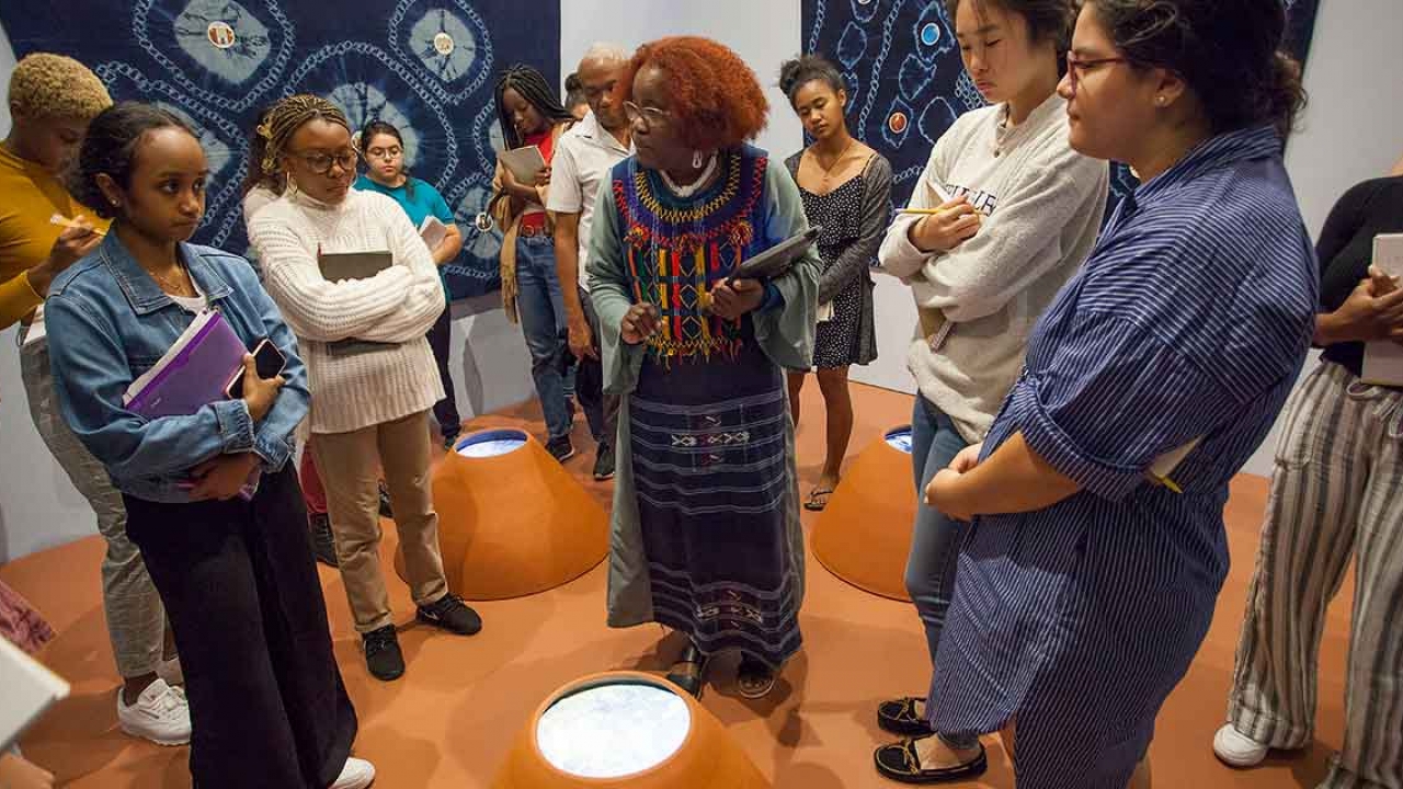 A group of people stand around a art exhibit in the Davis Museum