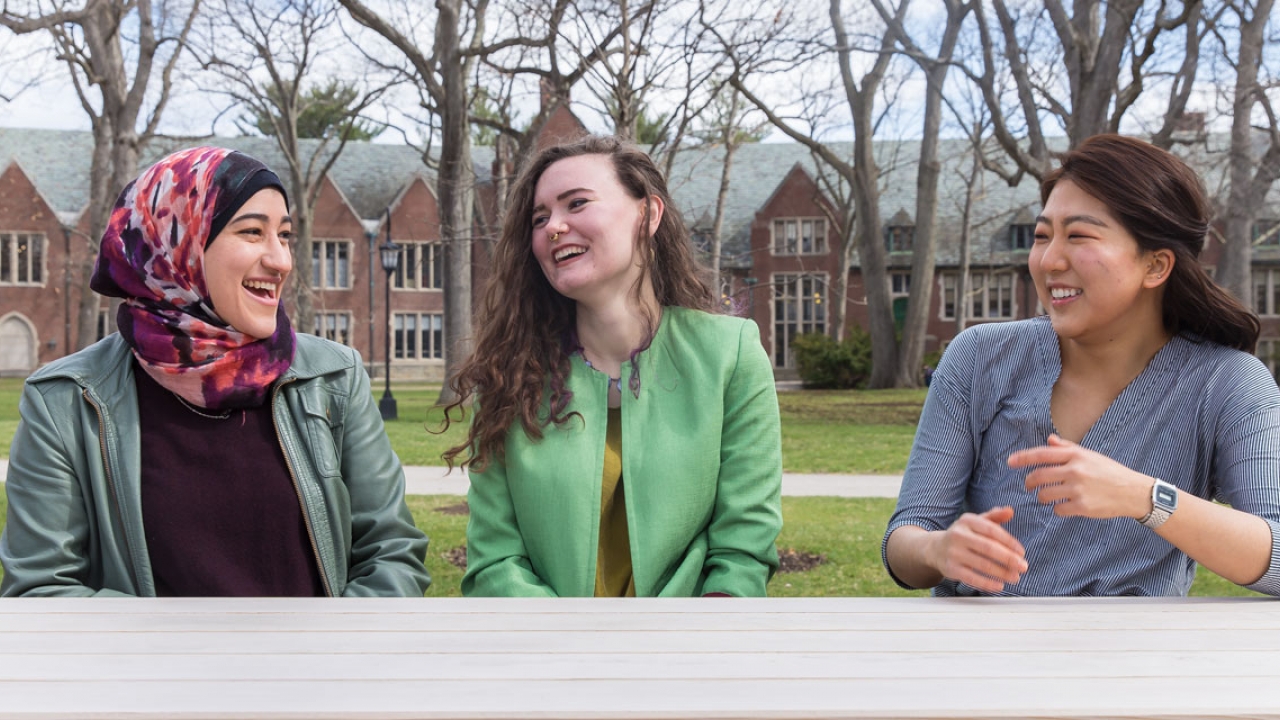Three Wellesley students who won the Watson Fellowship sit on campus, laughing.