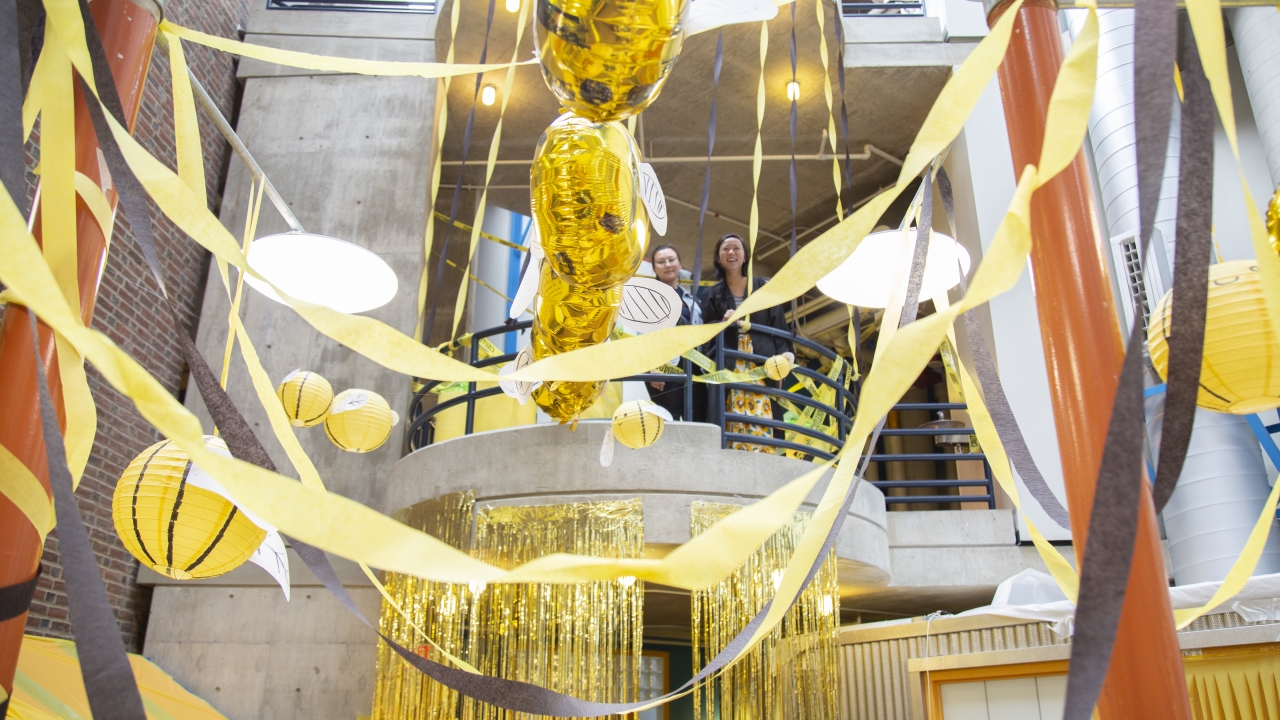Two students look down on a section of the science center that was decorated in yellow streamers. 