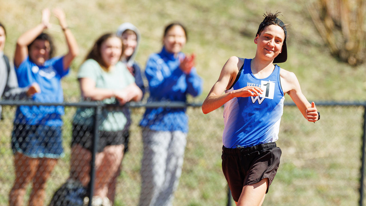 Ari Marks jogs around the new track at Wellesley and in the background spectators applaud.