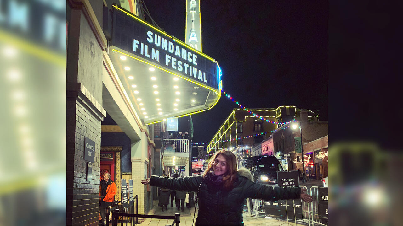 Claire Ayoub stands outside a Sundance sign with her arms outstretched.
