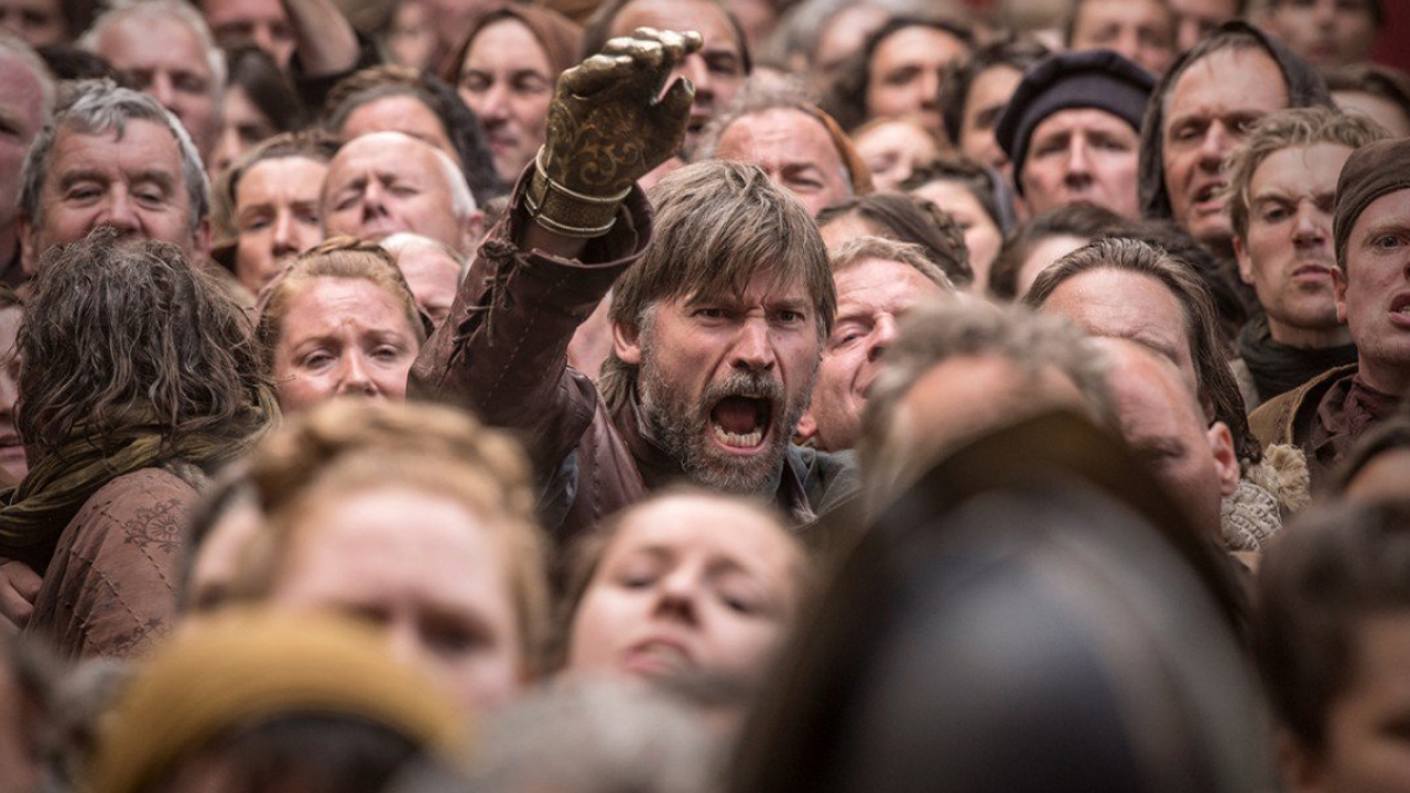 Game of Thrones character Jamie Lanister reaches from a crowd of peasants as he fights to break through. 