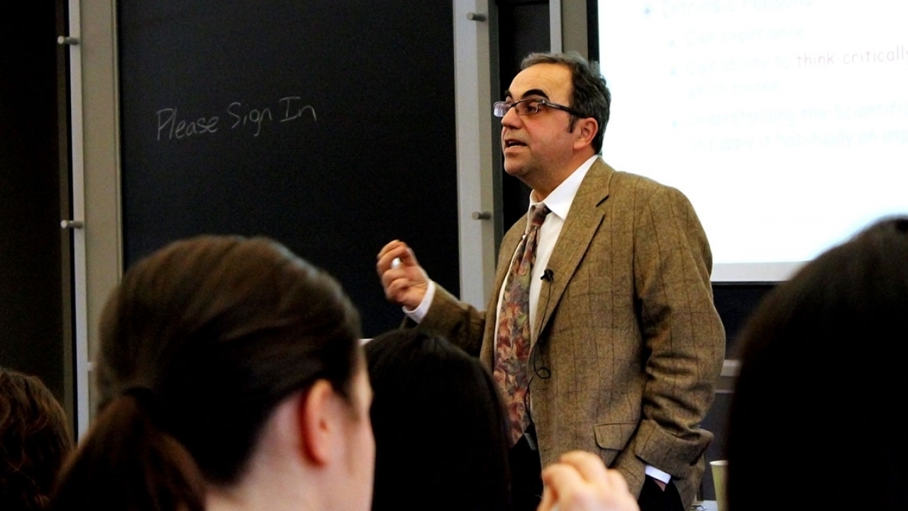 Professor Takis Metakas delivers a lecture at the front of a classroom.