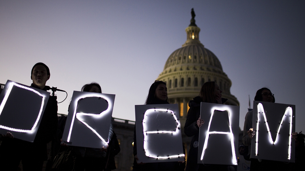 Protesters stand outside the Capitol building holding signs that read DREAM.