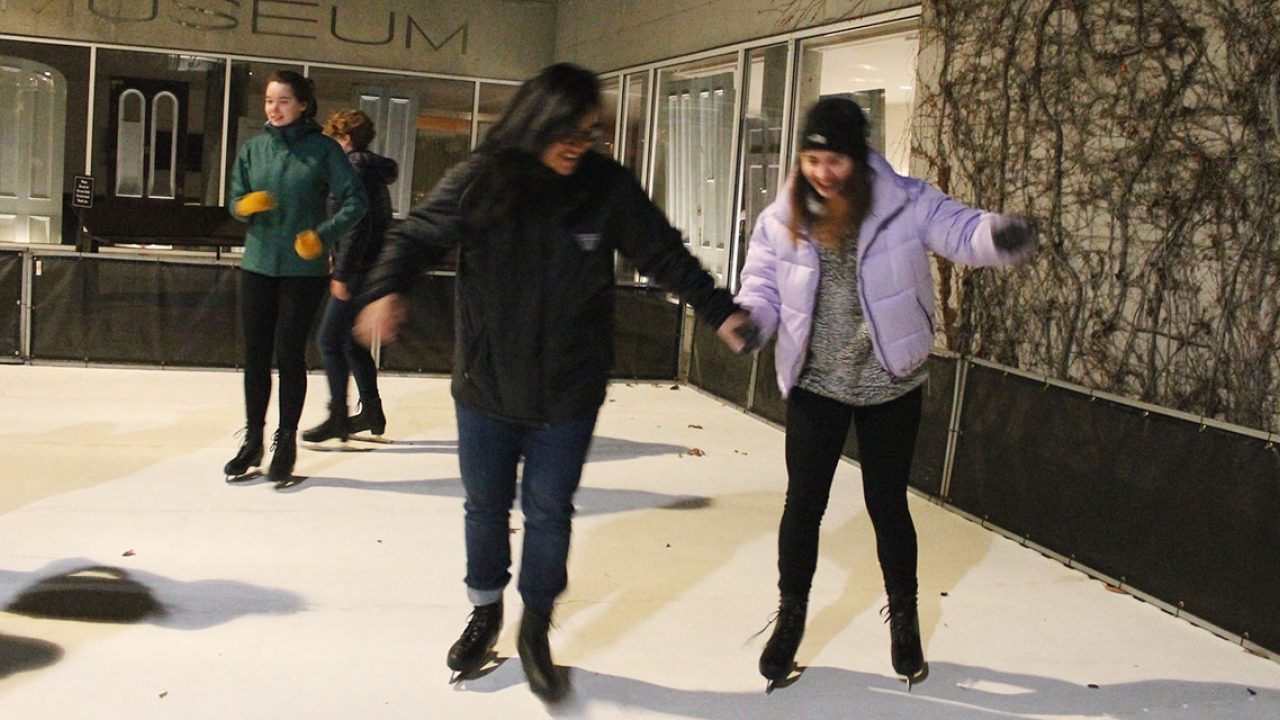 Two students ice skate on Davis Plaza