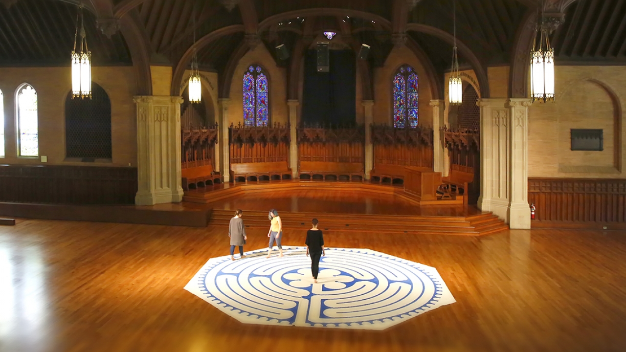 Three women walk a labyrinth inside Houghton Chapel. 