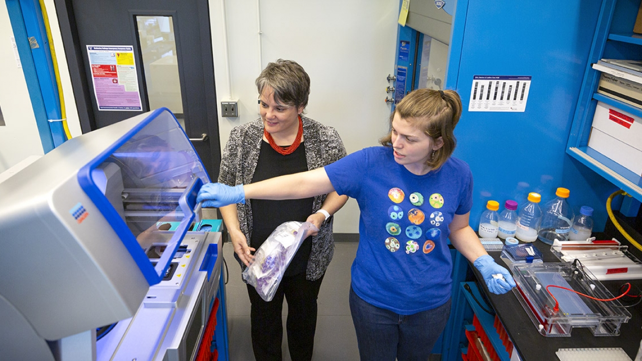 A professor and her student walk through a science lab
